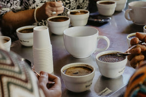 Group of people cupping coffee with white ceramics and spoons
